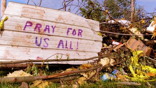 A piece of storm debris in Clearwater Florida painted with the words PRAY FOR US ALL after Hurricane Helene
